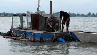 Zwei Männer arbeiten auf einem Saugbagger auf dem Altmühlsee. | Bild: BR