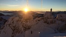 Blick vom Sendergebäude des BR auf dem Wendelstein auf das tief verschneite Voralpen-Panorama und die mit Nebel gefüllten Täler. Im Vordergrund die Wendelsteinkapelle, hinter den Bergen geht die Sonne unter.  | Bild: BR/Jürgen Schütz