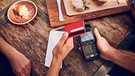Ein Gast bezahlt mit Karte nach dem Essen in einem Cafe.  | Bild: mauritius images / Yuri Arcurs / Alamy / Alamy Stock Photos