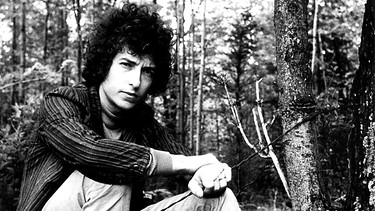 Circa 1965, New York, USA: Sänger Bob Dylan sitzt in einem Park. | Bild: picture alliance / Globe-ZUMA | Frank Dandridge